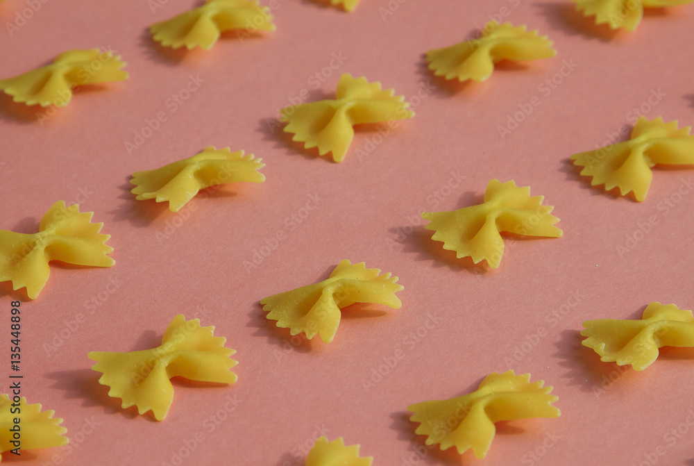 Makaroni or pasta bow shape in row on pink background Makaroni or pasta bow shape in row on pink background