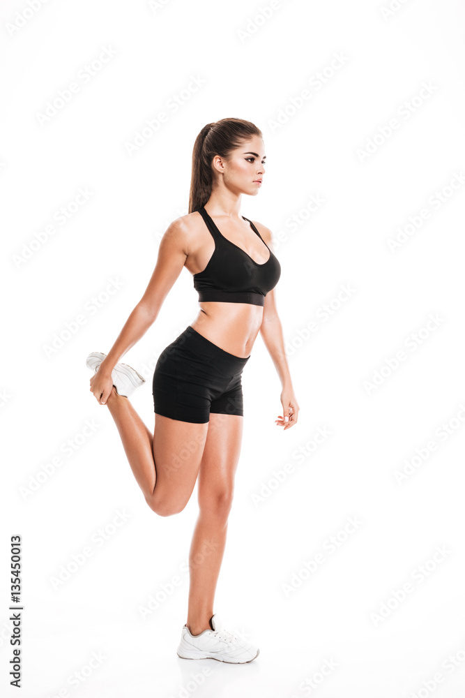 Full length of beautiful young sportswoman standing and stretching legs Full length of beautiful young sportswoman standing and stretching legs