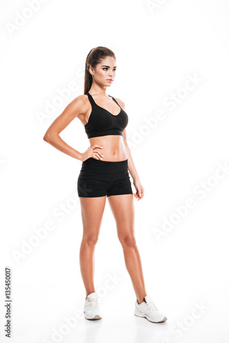 Full length of pretty young sportswoman in black sportswear