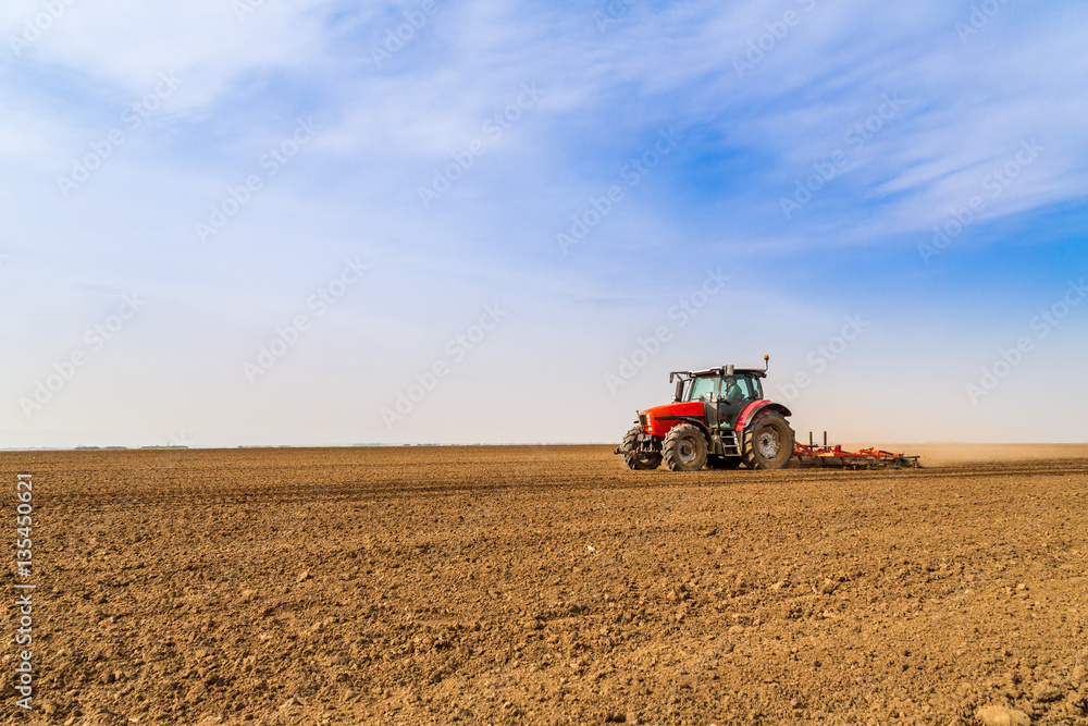 Fototapeta premium Farmer in tractor preparing land with seedbed cultivator