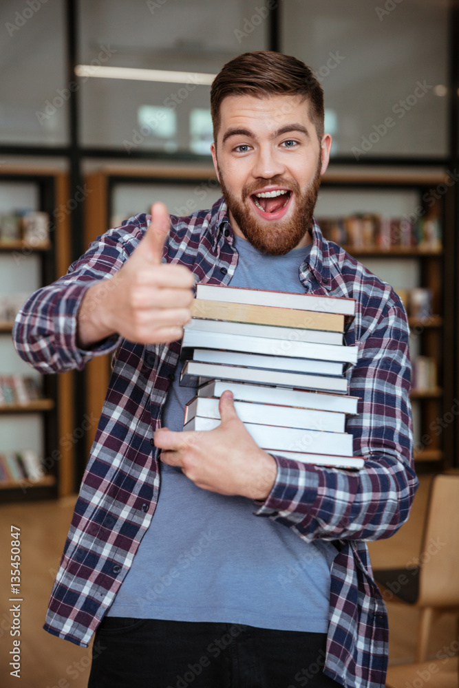 Obraz premium Portrait of a smiling man student holding books in library