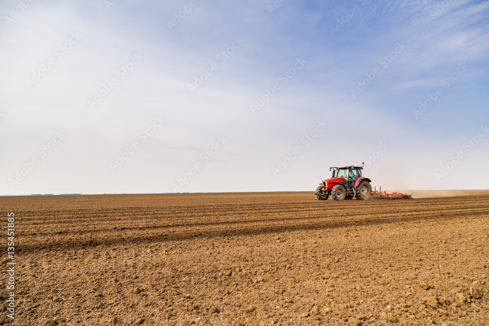 Obraz premium Farmer in tractor preparing land with seedbed cultivator