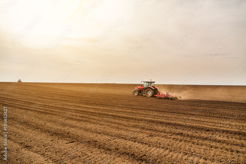 Farmer in tractor preparing land with seedbed cultivator Farmer in tractor preparing land with seedbed cultivator