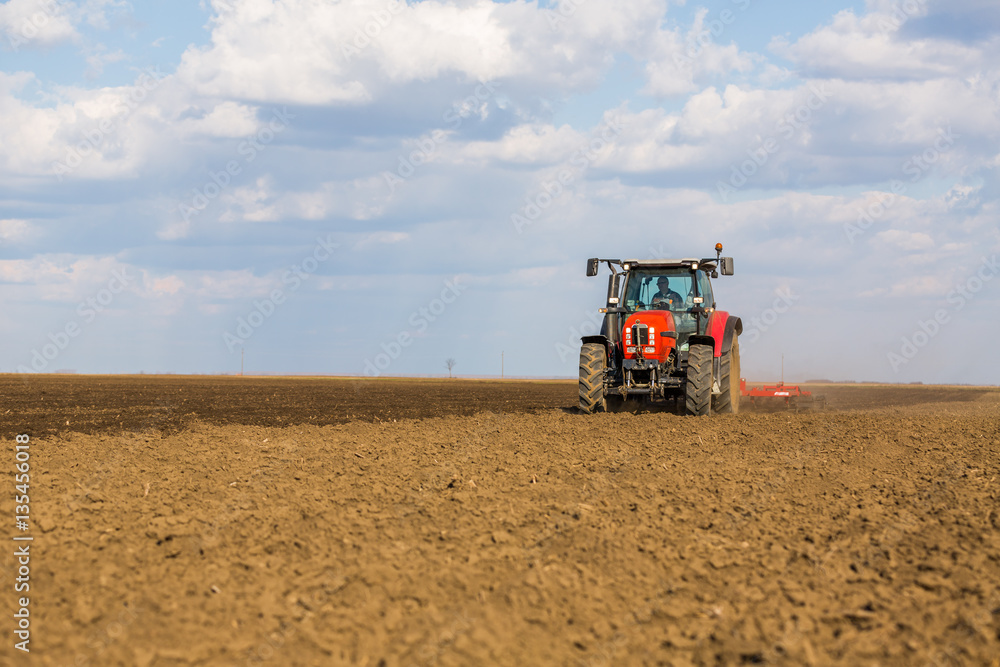 Farmer in tractor preparing land with seedbed cultivator Farmer in tractor preparing land with seedbed cultivator