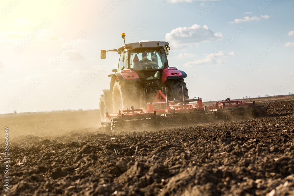 Obraz premium Farmer in tractor preparing land with seedbed cultivator as part of pre seeding activities in early spring season of agricultural works at farmlands.