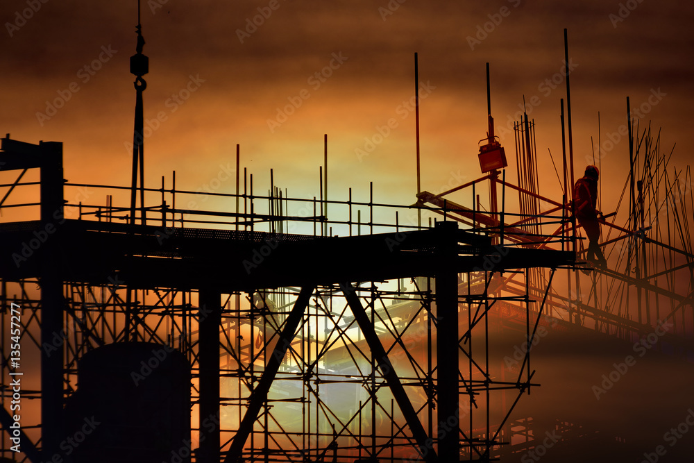 Silhouette construction worker , tower cranes build large residential buildings  at construction site industry .