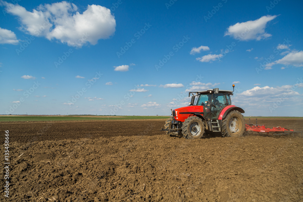 Farmer in tractor preparing land with seedbed cultivator as part of pre seeding activities in early spring season of agricultural works at farmlands. Farmer in tractor preparing land with seedbed cultivator as part of pre seeding activities in early spring season of agricultural works at farmlands.