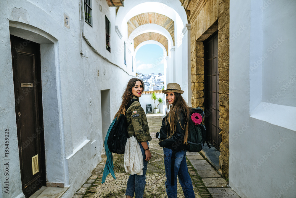 Spain, Andalusia, Vejer de la Frontera, two young women walking in the alley El Callejon de las Monjas