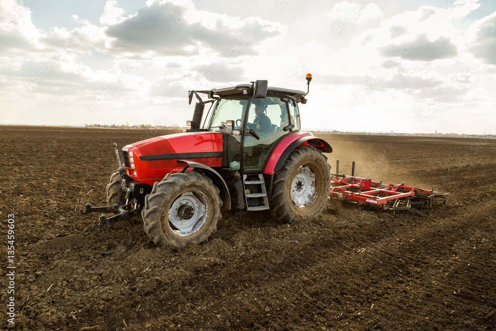 Farmer in tractor preparing land with seedbed cultivator as part of pre seeding activities in early spring season of agricultural works at farmlands. Farmer in tractor preparing land with seedbed cultivator as part of pre seeding activities in early spring season of agricultural works at farmlands.