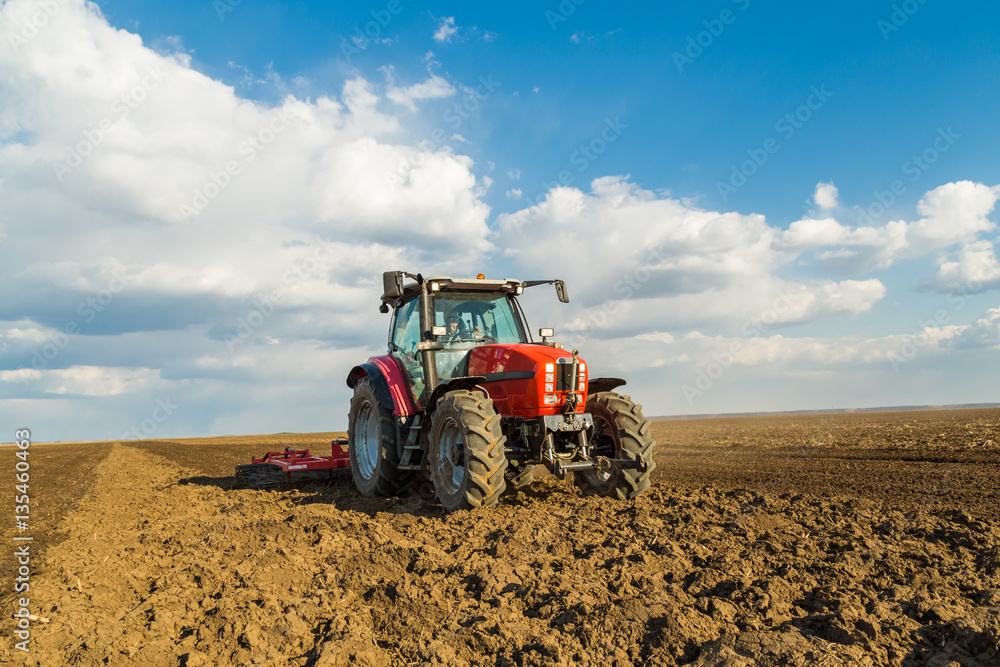 Farmer in tractor preparing land with seedbed cultivator as part of pre seeding activities in early spring season of agricultural works at farmlands. Farmer in tractor preparing land with seedbed cultivator as part of pre seeding activities in early spring season of agricultural works at farmlands.