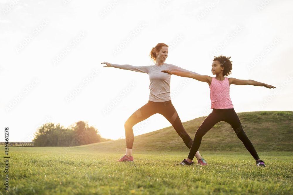 Mother and daughter doing yoga in meadow Mother and daughter doing yoga in meadow
