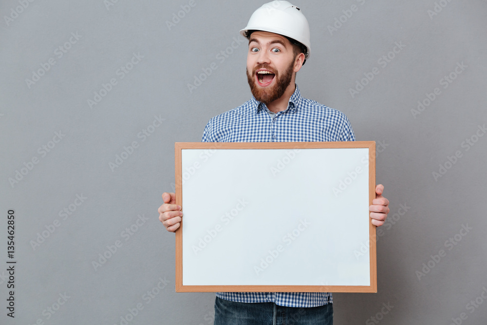Happy bearded builder holding copyspace board Happy bearded builder holding copyspace board