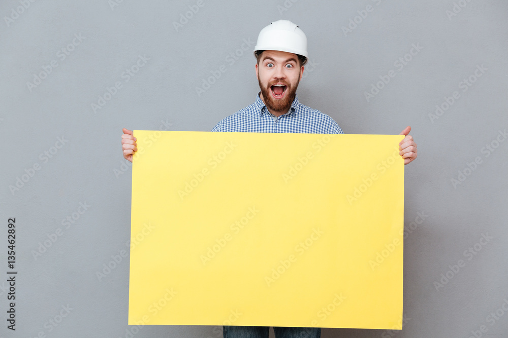 Amazing young bearded builder holding copyspace board Amazing young bearded builder holding copyspace board