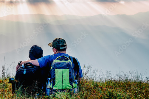 young adult asian couple sitting together enjoys rise to the top of the mountain with light of evening in vintage style
