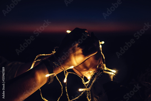couple holding hands together with decorate light