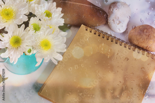 Blank area note book or diary with flower and pebble and water drop