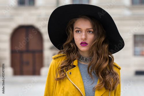 Fashionable brunette woman wearing hat and yellow jacket