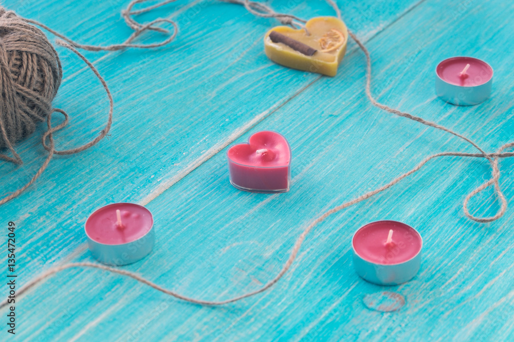Greeting card with blue wooden shabby background with heart, candles and a skein of thread. Shallow Selective focus. Copyspace. Greeting card with blue wooden shabby background with heart, candles and a skein of thread. Shallow Selective focus. Copyspace.