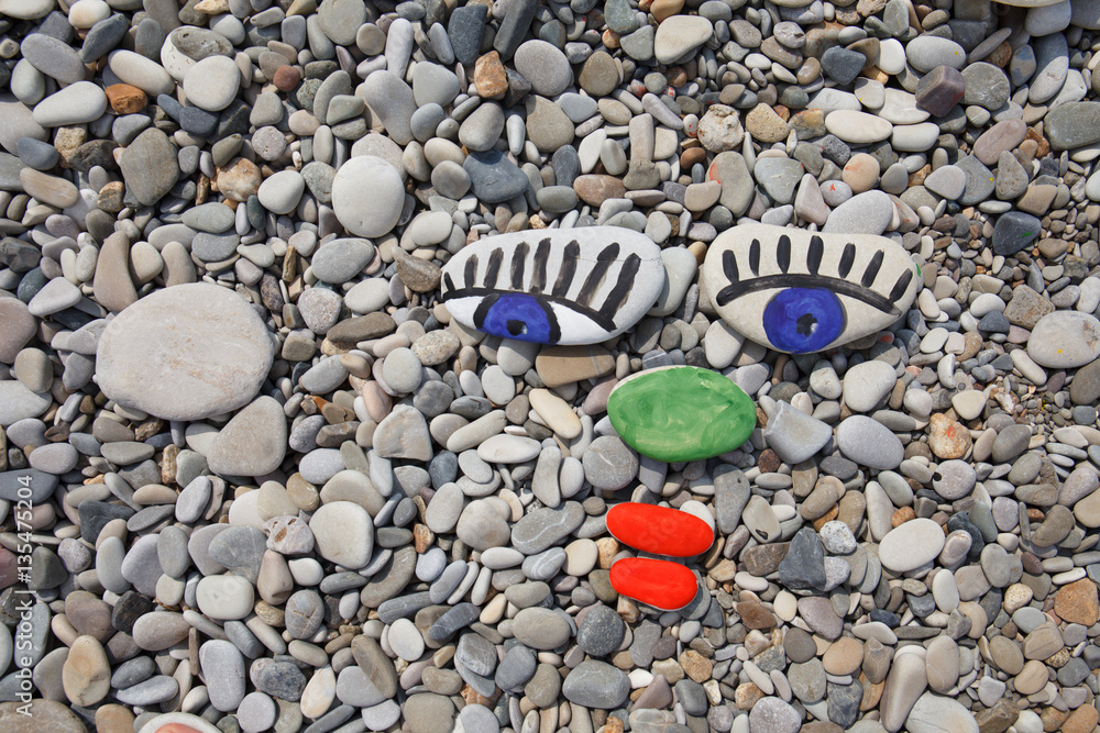 Sea smooth stones, pebbles with human face, stone painting on th