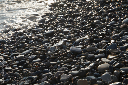 wet Zen pebble on a beach at sun day