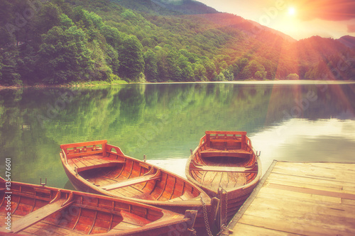 View of glacial mountain Lake Biogradsko, wooden pier and boats in forest. Biogradska Gora National Park. Montenegro. Filtered image:cross processed vintage effect. photo