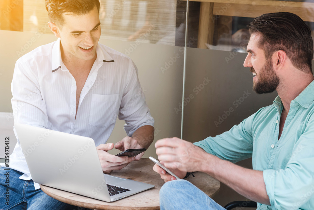 Obraz premium Two Westerner Business men working with laptop and smartphone to
