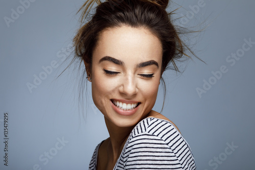 Slika na platnu Closeup portrait of young woman with toothy smile in studio