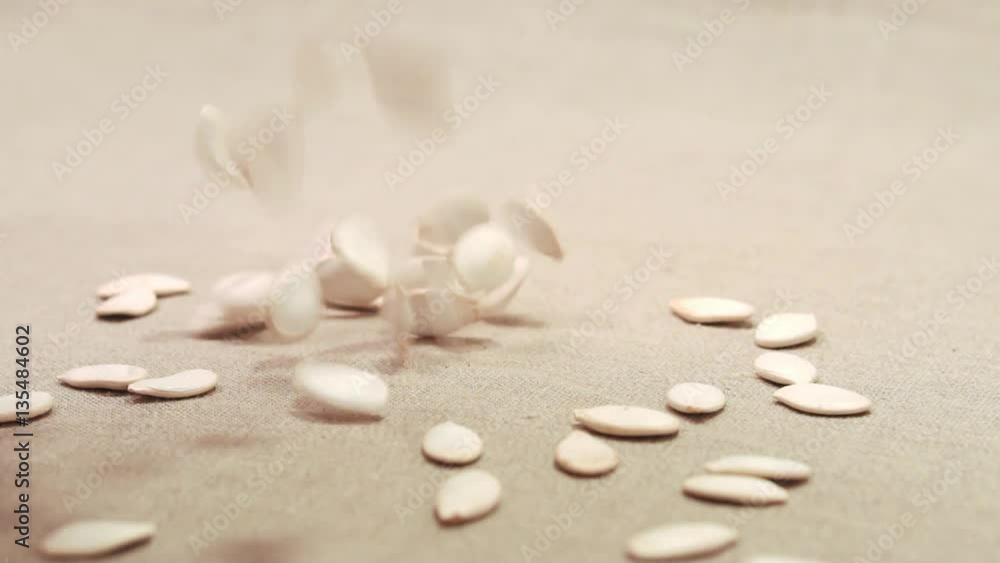Pumpkin seeds falling down on a linen fabric Pumpkin seeds falling down on a linen fabric