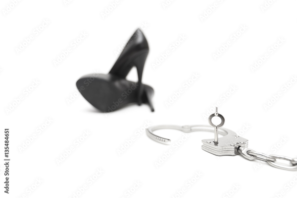 High Heels mit Handschellen auf weißem Hintergrund High Heels mit Handschellen auf weißem Hintergrund