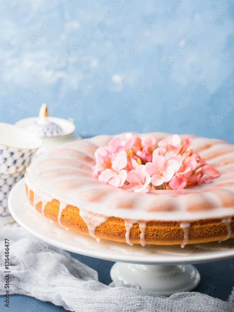Bundt ring cake with sugar frosting decorated with pink flowers. Spring summer elegant breakfast set. Easter mother day festive treat. Selective focus