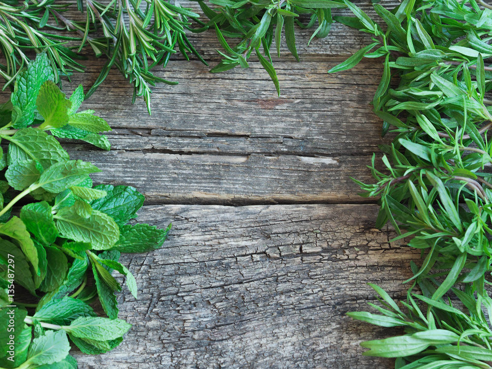 Obraz premium Frame of fresh herbs - rosemary, savory, mint on an old wooden background 