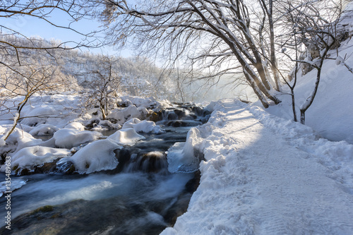 Winter path covered by snow and river flowing thru plitvice lake, Croatia