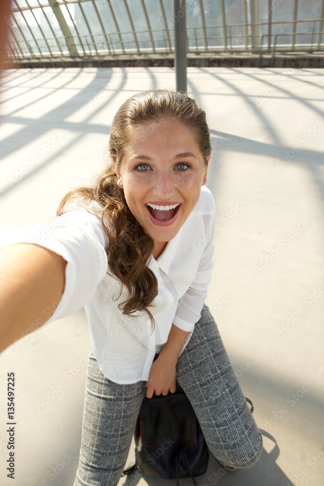 young woman sitting on suitcase taking herself photo young woman sitting on suitcase taking herself photo