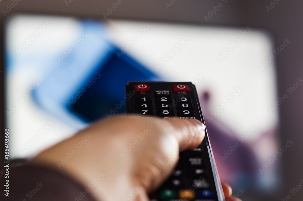 TV remote control, the hand with a remote control. - obrazy, fototapety, plakaty 