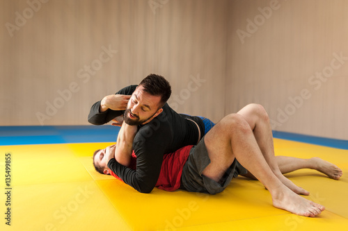 Mixed martial artist trying to choke his opponent on the mat
