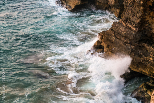 Waves Crashing Against Rocky Cliff