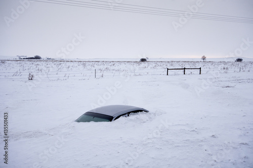 Car buried to its roof in deep snow not far from the road. North Dakota, USA
