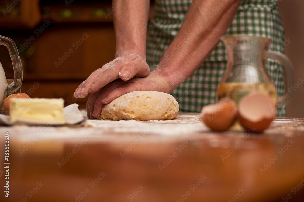 man hands knead dough on a table in her home kitchen man hands knead dough on a table in her home kitchen