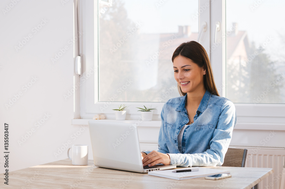 Smiling woman working on laptop at home Smiling woman working on laptop at home