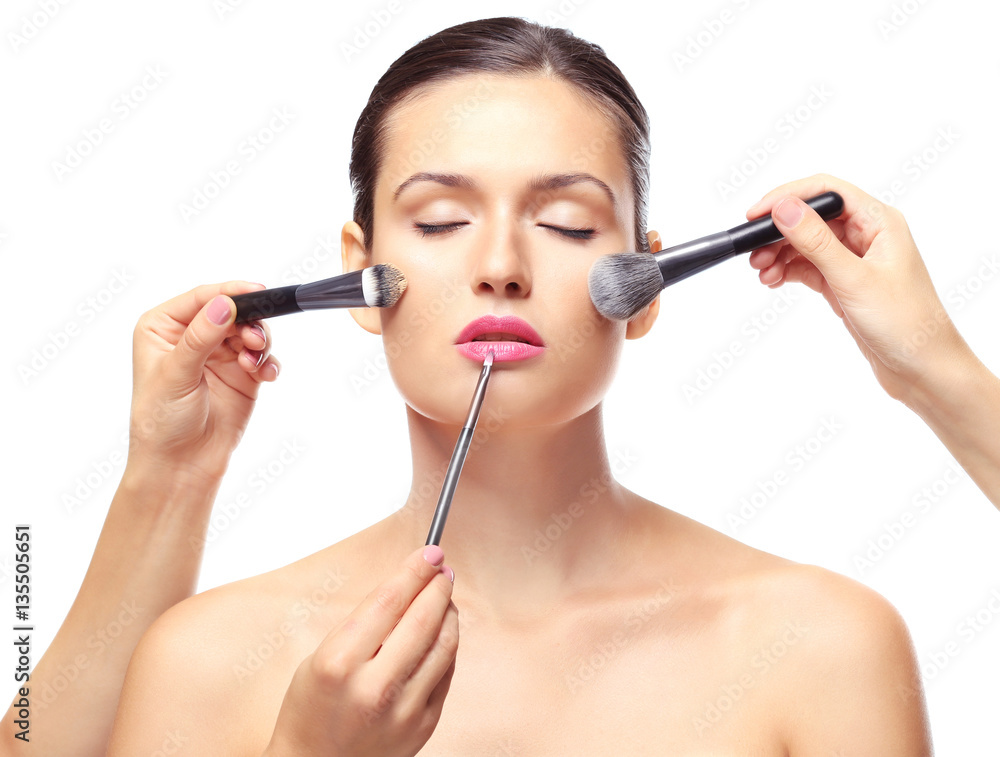 Beautiful girl applying cosmetics on white background