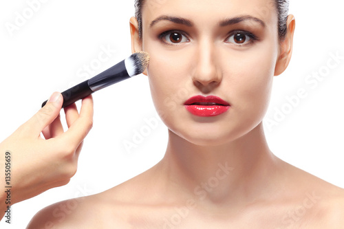Beautiful girl applying cosmetics on white background
