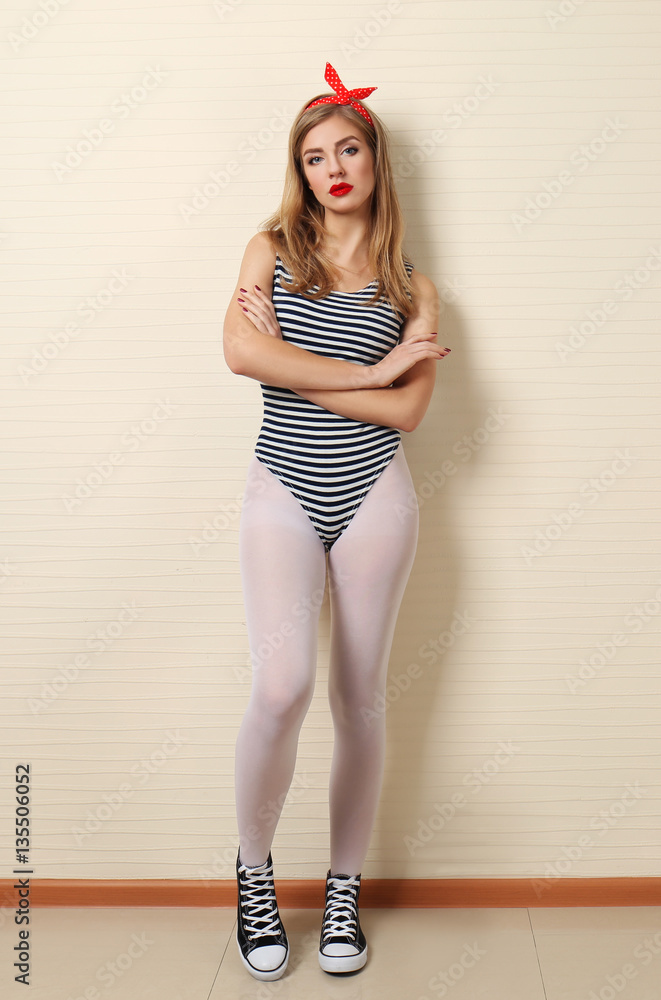 Woman in white tights and sneakers on light wall background Stock