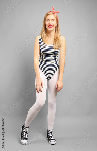 Woman in white tights and sneakers on gray background