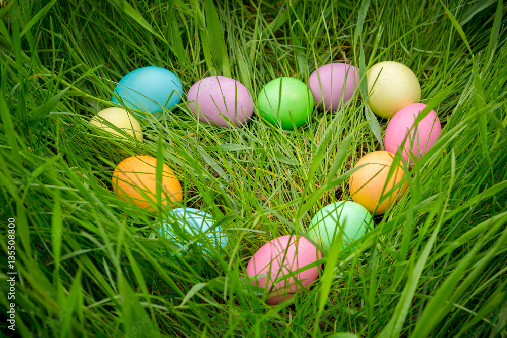 background with colorful easter eggs on meadow in heart shape background with colorful easter eggs on meadow in heart shape