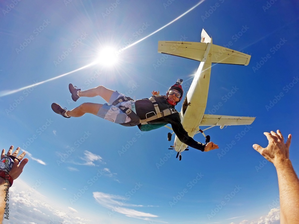 Funny parachutist jumps from an airplane on a summer day. Point of view - obrazy, fototapety, plakaty 