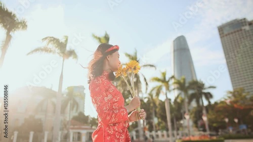 Girl in traditional Vietnamese dress spinning happy with yellow flowers. The mood of delight. Vietnam. photo