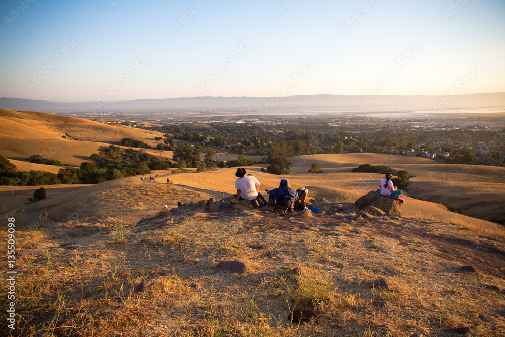 Obraz premium Family sits on top of a hill in Fremont, California to watch the sunset and fireworks