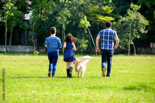 Back view of a family with a dog running away