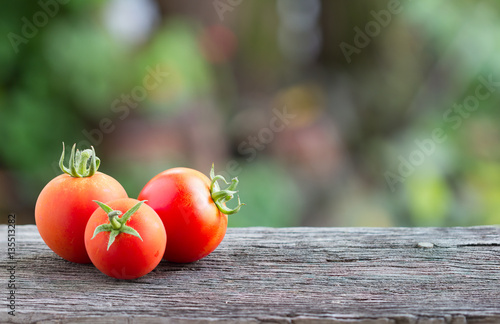 Glass bottle of fresh healthy juice with tomatoes on wooden back