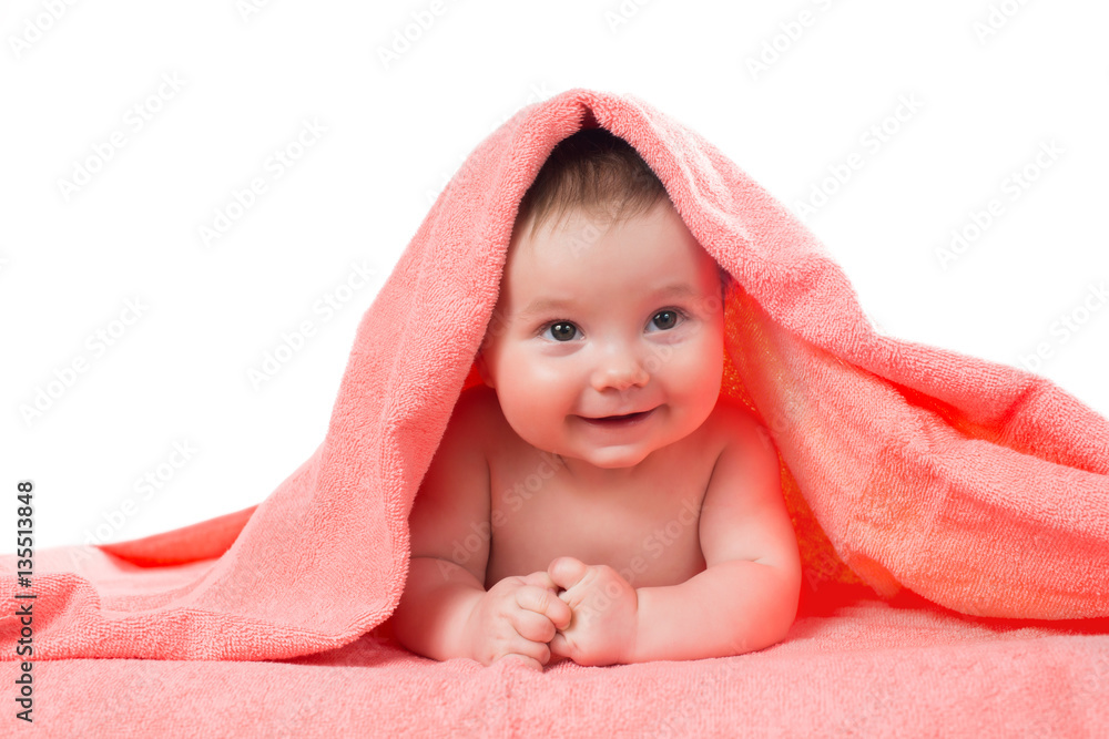 Newborn baby lying down and smiling in a terracotta color towel Newborn baby lying down and smiling in a terracotta color towel